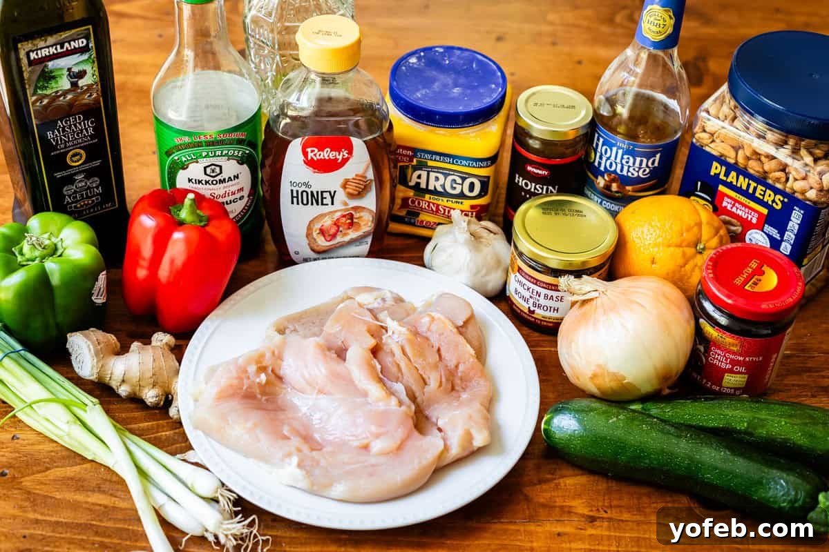 Szechuan Kung Pao Chicken 7 A flat lay photograph displaying all the fresh and pantry ingredients needed for a delicious Kung Pao chicken stir-fry: colorful bell peppers, zucchini, chicken, peanuts, and various sauce components.