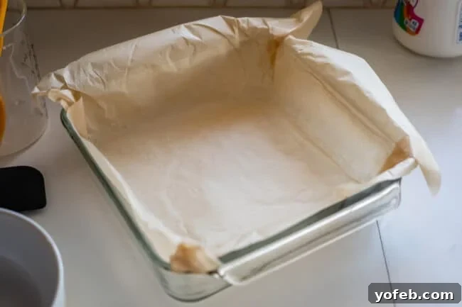 Mom's Effortless Fudge 13 A square glass pan carefully lined with brown parchment paper, corners folded neatly, ready to receive the fudge mixture.