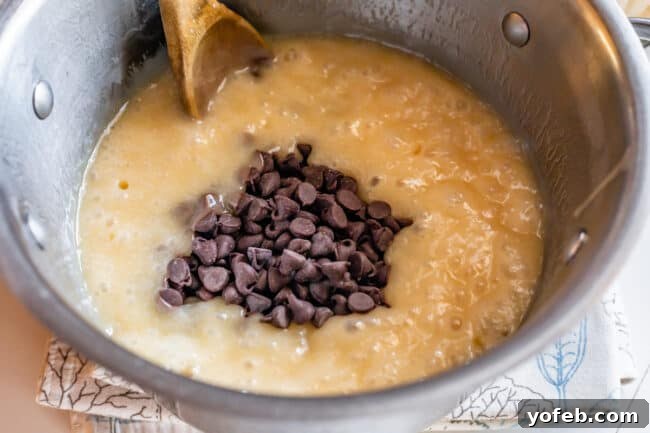 Mom's Effortless Fudge 19 Chocolate chips being poured into the hot, boiled fudge mixture, ready to be stirred until completely melted and smooth.