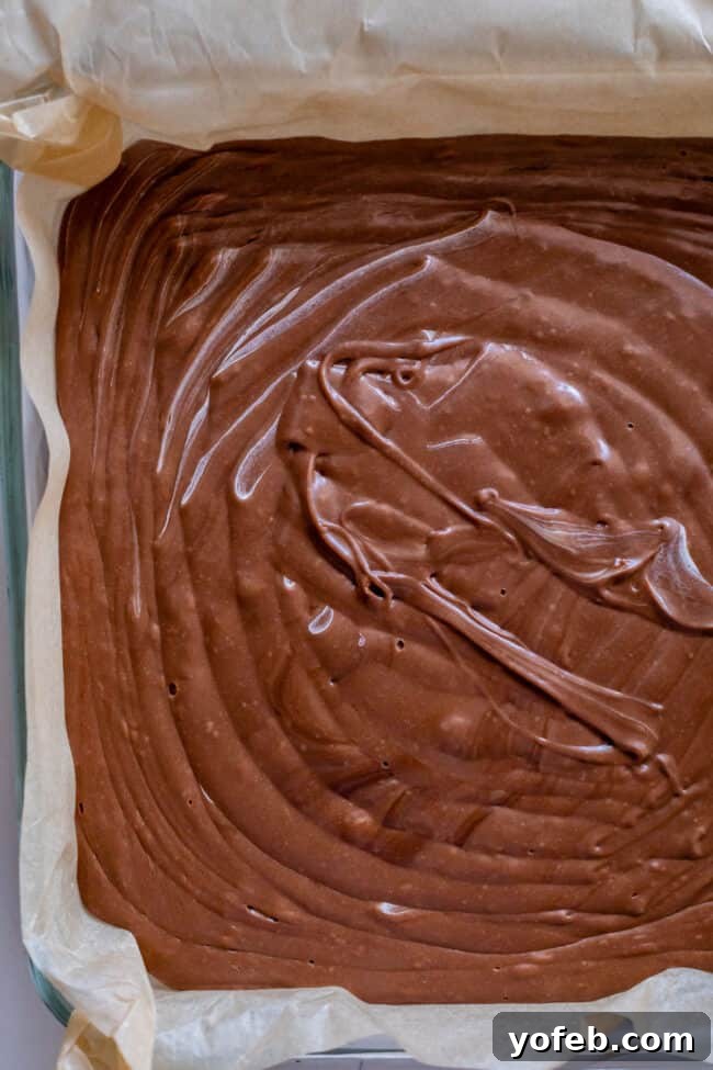 Mom's Effortless Fudge 27 An overhead view of rippled fudge in a parchment-lined pan, its surface perfectly textured as it begins to cool.