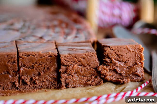 Mom's Effortless Fudge 30 Marshmallow fluff fudge squares on parchment paper, adorned with a festive red string, signaling a delightful homemade treat.
