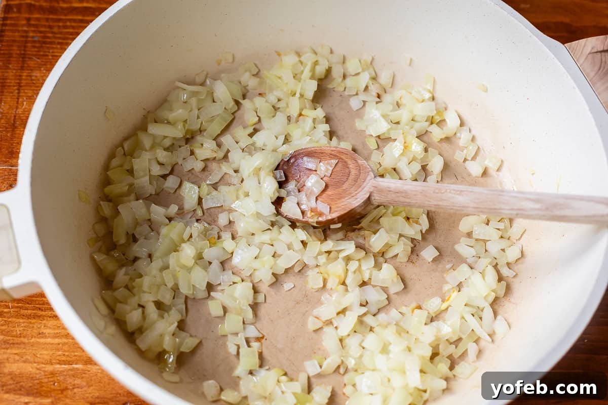 Grandma Prudy's Timeless Swedish Meatballs 12 Finely chopped onions sautéing in a large skillet, being gently stirred with a wooden spoon, becoming soft and translucent.