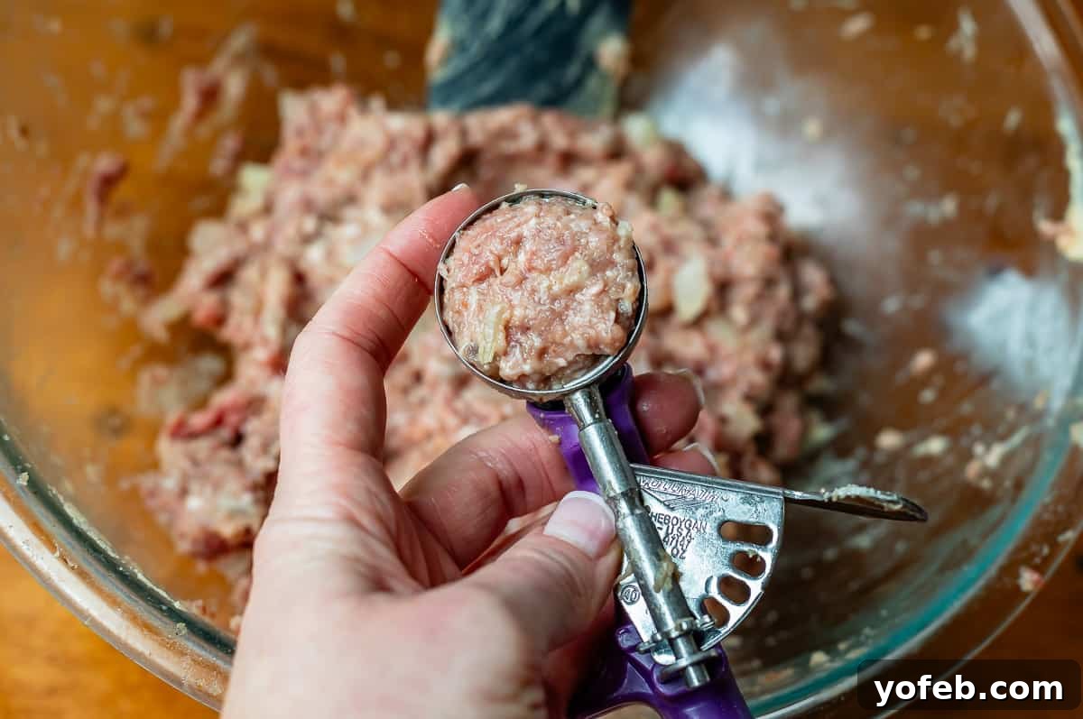 Grandma Prudy's Timeless Swedish Meatballs 15 Uncooked meatball mixture being pressed into a small cookie scoop to ensure uniform size and shape.
