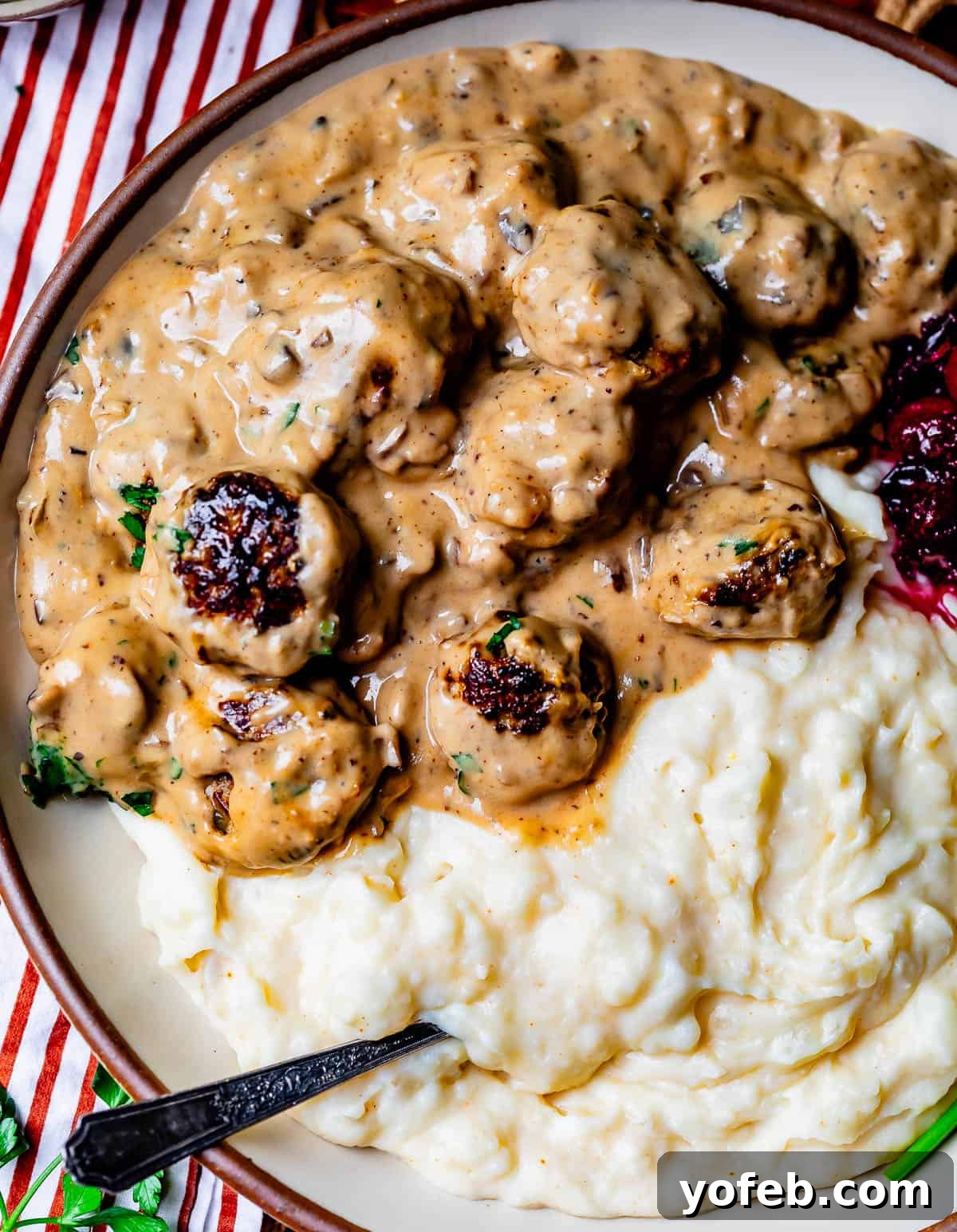 Grandma Prudy's Timeless Swedish Meatballs 21 A plate, perfectly divided, with one half filled with fluffy mashed potatoes and the other half with saucy Swedish Meatballs and creamy gravy.