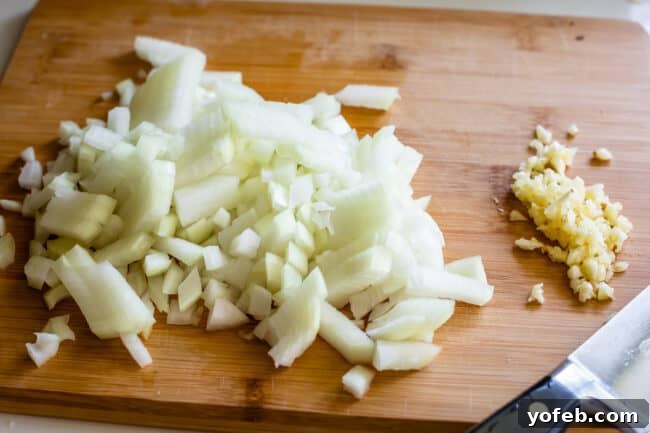 Effortless Creamy White Chicken Chili 11 Chopped onions and minced garlic on a cutting board, ready for sautéing.