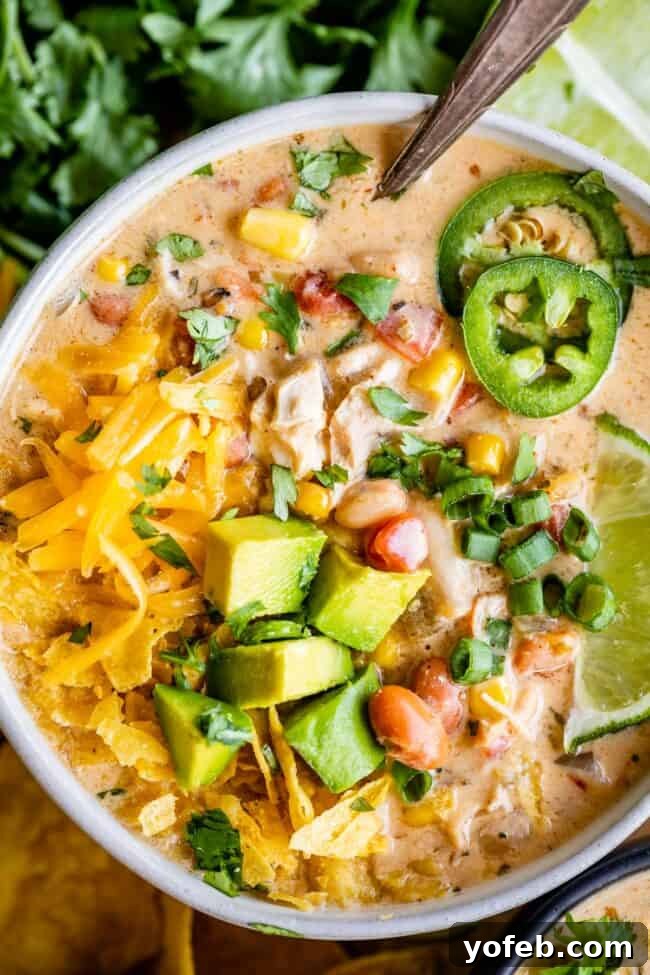 Effortless Creamy White Chicken Chili 3 White chicken chili in a rustic bowl on a wooden board, garnished with fresh jalapeños.