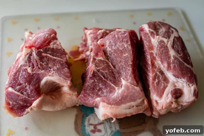 Slow Cooker Pork Ramen Deep Flavor Zero Fuss 8 pork shoulder on a cutting board, chopped into 3
