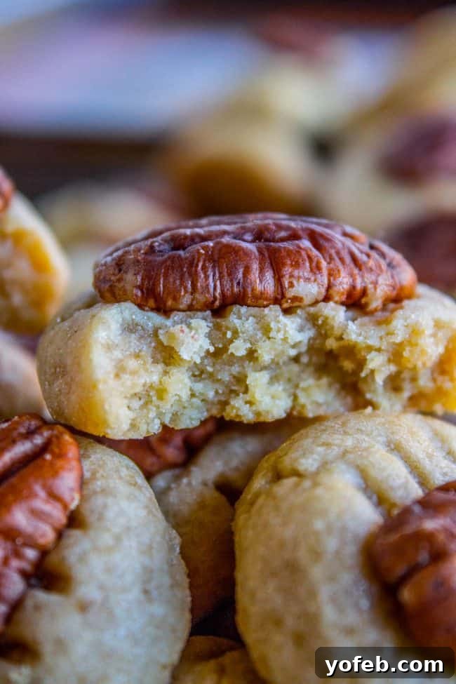 A stack of golden-brown butter pecan cookies, with one missing a bite, showcasing their delectable texture.