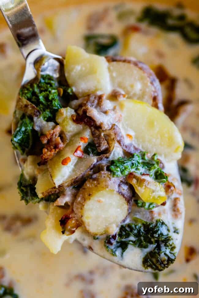 Spoonful of Zuppa Toscana with Potatoes and Sausage A spoonful of Zuppa Toscana, lifting tender potatoes, sausage, and kale from the creamy broth.