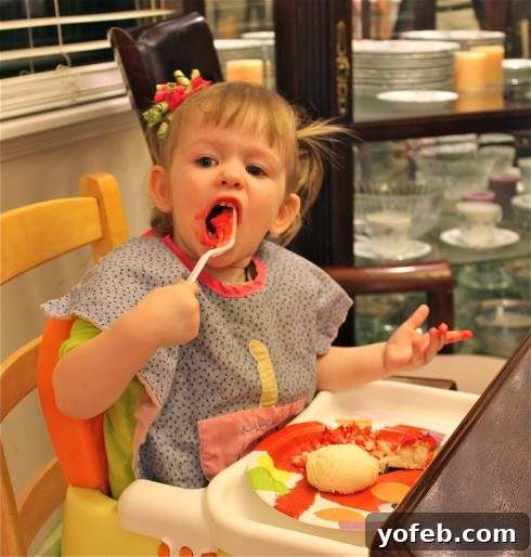 How to Make an Elmo Cake The Easy Way No Cake Pan Required 6 A child joyfully eating a piece of Elmo cake, showing red frosting on their face.