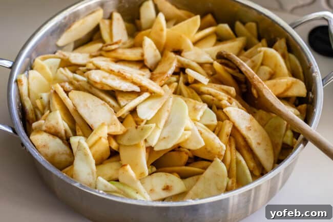The Ultimate Dutch Apple Pie 18 Raw, sliced apples are mixed with spices and flour in a deep pan, ready for cooking to create the luscious pie filling.