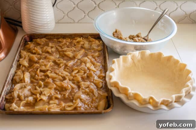 The Ultimate Dutch Apple Pie 25 A curated shot showing all chilled pie components: apple pie filling on a sheet pan, a crimped pie crust in its dish, and streusel topping in a bowl, ready for assembly.