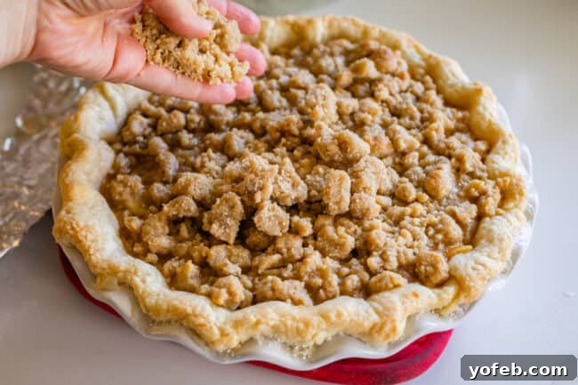 The Ultimate Dutch Apple Pie 27 Adding an extra layer of chilled streusel crumb topping to a partially baked apple pie, ensuring a thick, golden crust.