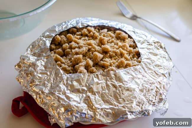 The Ultimate Dutch Apple Pie 28 A homemade tin foil pie crust cover, expertly placed over a Dutch apple pie to shield the edges of the crust from burning during baking.
