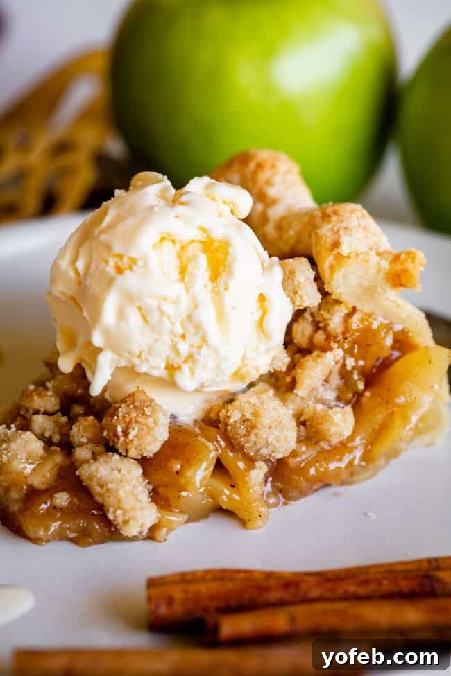 The Ultimate Dutch Apple Pie 9 A slice of Dutch apple pie on a white plate, served alongside a scoop of creamy vanilla ice cream, creating a perfect dessert pairing.