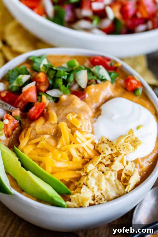 Creamy Chicken Enchilada Soup (Chili's Copycat Recipe) from The Food Charlatan. This dreamy Creamy Chicken Enchilada Soup tastes like the kind at Chili's, only better! It is a simple soup that has a unique flavor thanks to Masa Harina (corn flour). There are no veggies in the soup; instead you make Pico de Gallo and serve it as a generous topping! It's one of my all time favorite soups! #chicken #dinner #recipe #easy #enchilada #enchiladasoup #chickensoup #creamy #cheesy #stovetop #Chilis chicken enchilada soup with garnishes.