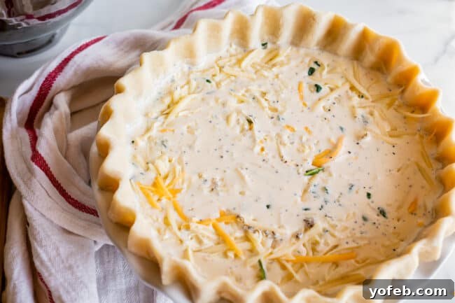 Effortless Bacon and Spinach Quiche 19 An unbaked quiche sits beautifully in a pie shell, accompanied by a white and red patterned napkin, ready for the oven.