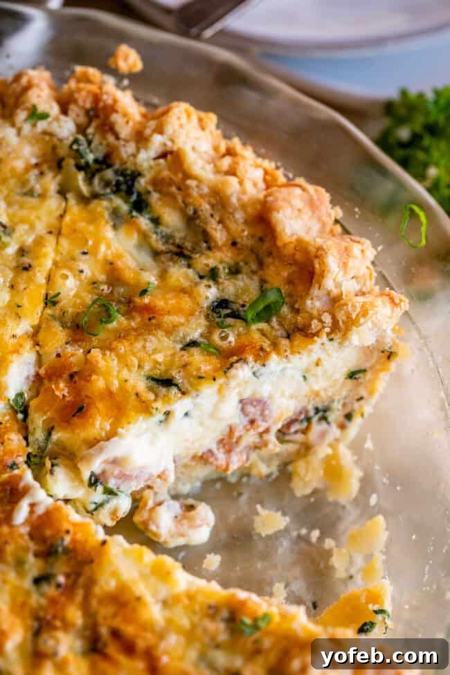 Effortless Bacon and Spinach Quiche 25 A warm ham and cheese quiche, baked in a clear glass pie pan, with a missing slice revealing its rich layers.