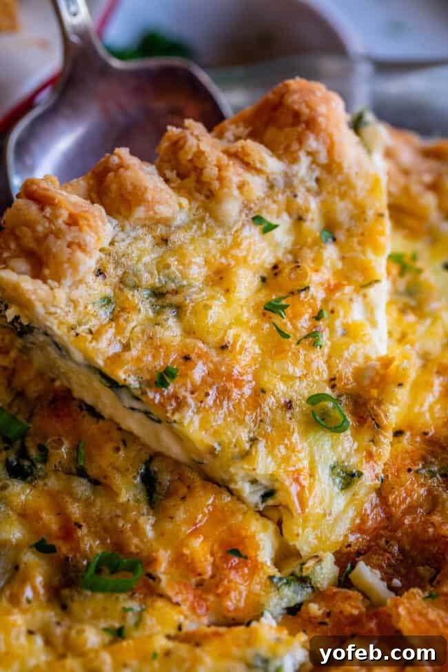 Effortless Bacon and Spinach Quiche 4 A spatula delicately lifts a generous slice of basic quiche, revealing its cheesy, custardy interior and crispy edges, garnished with fresh green onion.