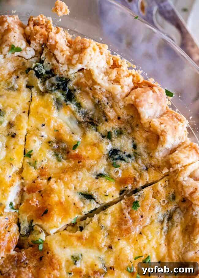 Effortless Bacon and Spinach Quiche 6 An inviting overhead shot of a slice of spinach quiche nestled in a clear glass pie pan, highlighting its vibrant green spinach and golden cheese.