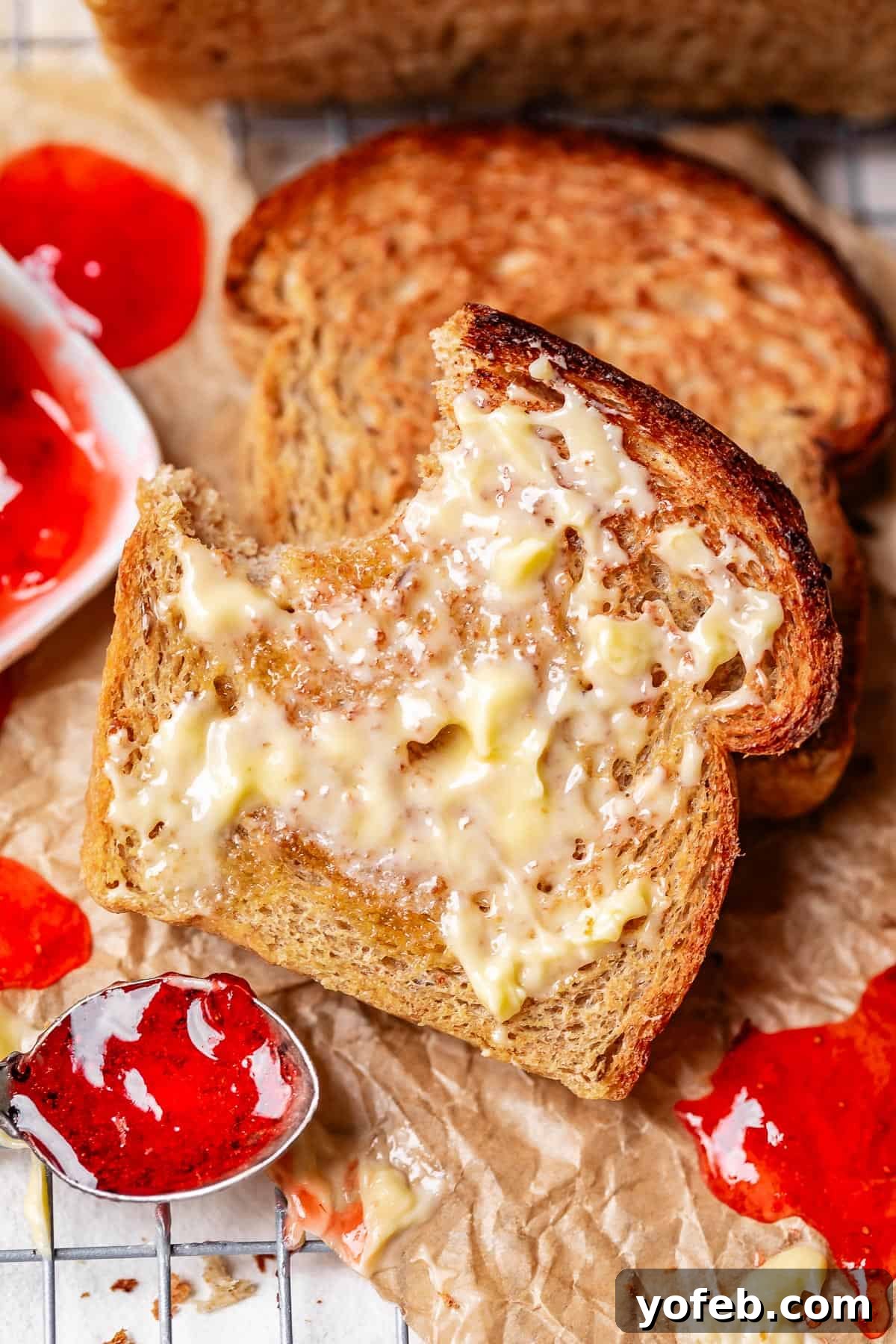Grandma Prudy's Heirloom Rye Loaf 32 A slice of buttered rye toast with a bite taken out, inviting a delicious experience.