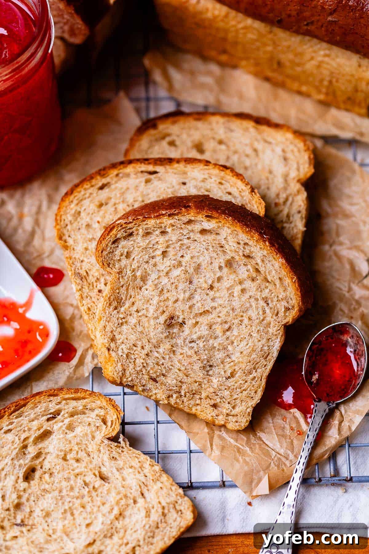Grandma Prudy's Heirloom Rye Loaf 5 Slices of fluffy rye bread neatly arranged on parchment paper on a cooling rack.