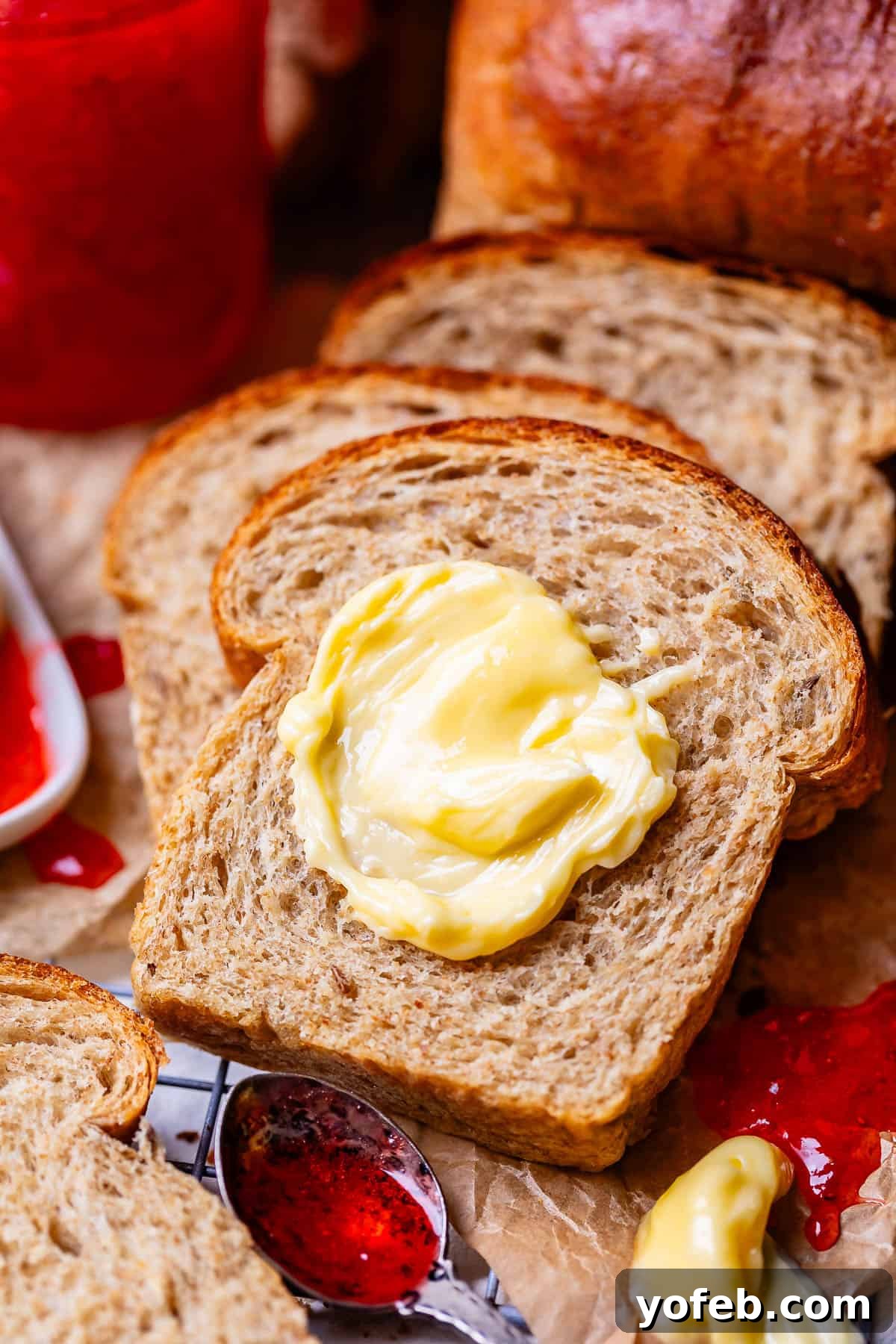 Grandma Prudy's Heirloom Rye Loaf 9 A slice of rye bread, buttered and served with a spoonful of red jam, showcasing its versatility.