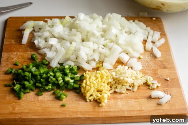 Flavorful Chicken Curry Made Easy 15 onions, jalapeno, garlic, ginger, chopped on a cutting board.