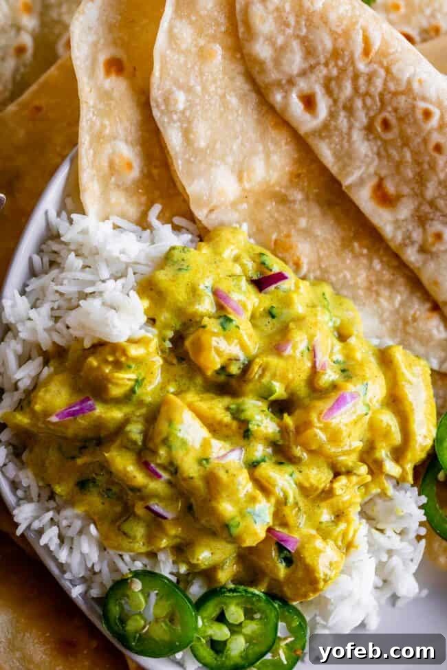 Flavorful Chicken Curry Made Easy 22 chicken curry on top of rice garnished with jalapenos and red onions and roti.