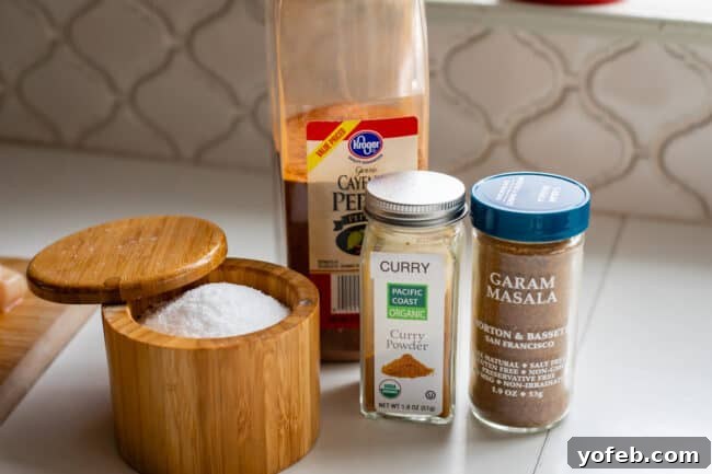 Flavorful Chicken Curry Made Easy 10 salt, cayenne, curry, and garam masala lined up in bottles on a counter.