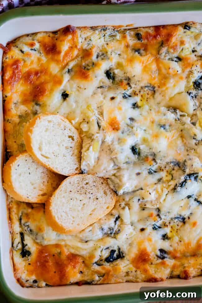 Ultimate Cheesy Spinach Artichoke Dip 18 Easy spinach artichoke dip in a vibrant green dish, adorned with three perfectly placed toasted bread slices.