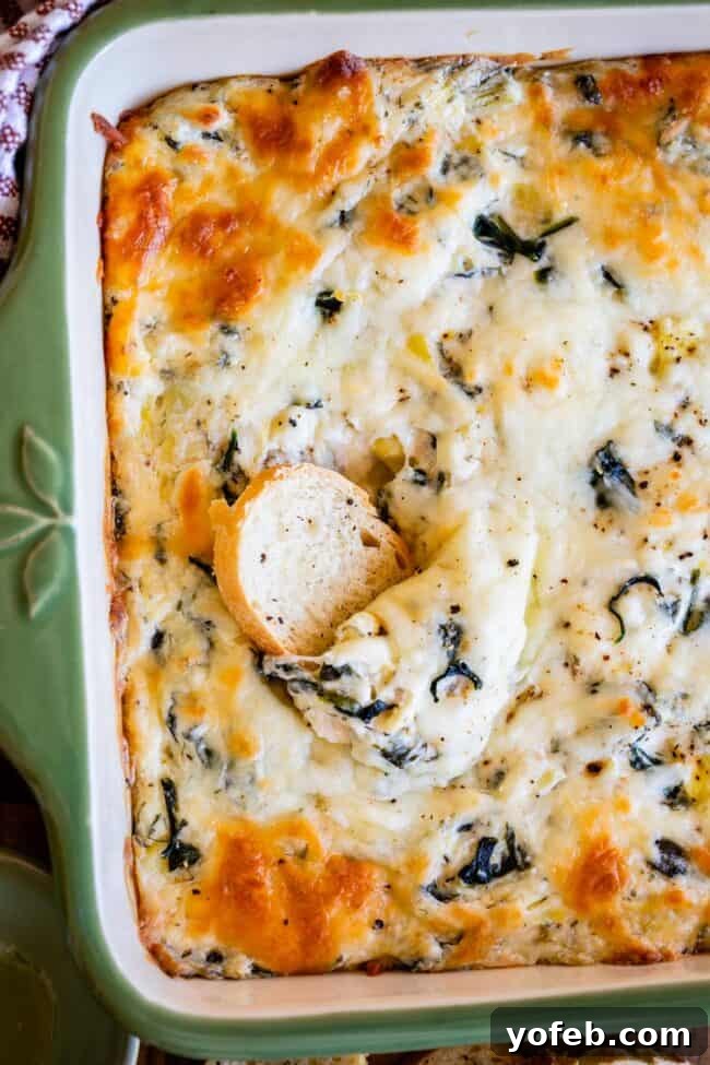 Ultimate Cheesy Spinach Artichoke Dip 3 Bread slice perfectly scooped into the center of a pan of warm spinach artichoke dip.