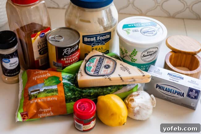 Ultimate Cheesy Spinach Artichoke Dip 9 A vibrant flat lay showcasing all the essential spinach artichoke dip ingredients: parmesan, cream cheese, fresh spinach, lemon, garlic, mayonnaise, sour cream, and various spices.