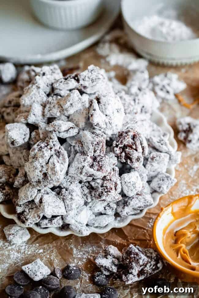 Loaded Chunky Chex Muddy Buddies 22 A plate of freshly made puppy chow, featuring various chunky clusters and individual pieces, alongside a bowl of creamy peanut butter.