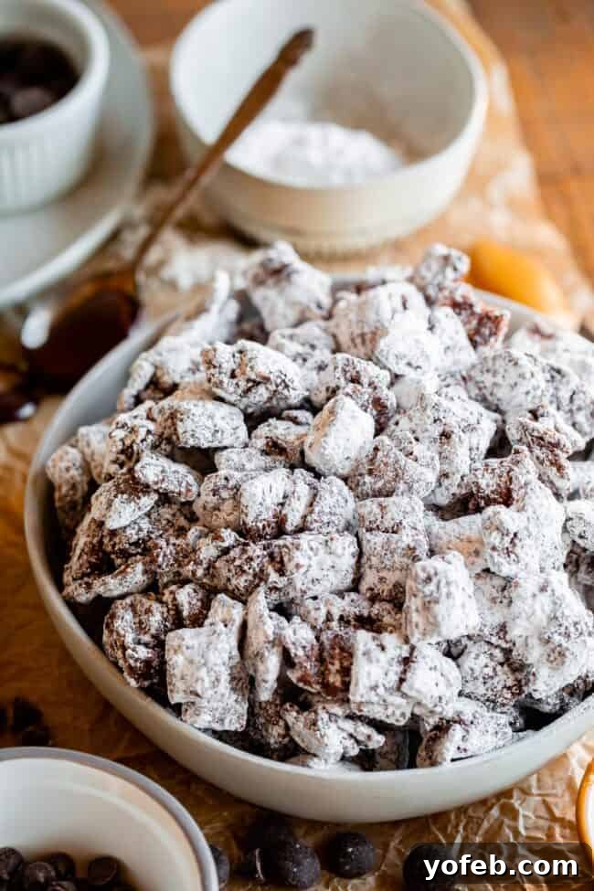 Loaded Chunky Chex Muddy Buddies 10 A large white bowl filled with finished Muddy Buddies (Puppy Chow), showcasing the generous powdered sugar coating.