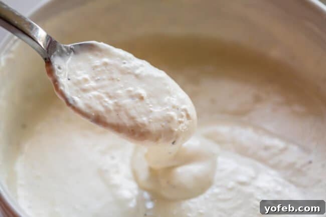 Fiery Homemade Horseradish Sauce 12 horseradish sauce being lifted from a bowl with a spoon.