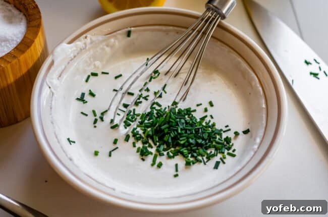 Fiery Homemade Horseradish Sauce 13 adding chopped chives to a bowl of horseradish sauce.