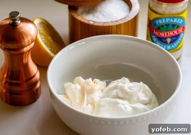 Fiery Homemade Horseradish Sauce 8 sour cream and mayo in a bowl, surrounded by pepper, lemon, salt, horseradish.