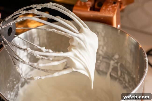 Luscious Banana Cream Pie Recipe 17 Fluffy homemade whipped cream clinging to the whisk attachment of a stand mixer, indicating perfect stiffness.