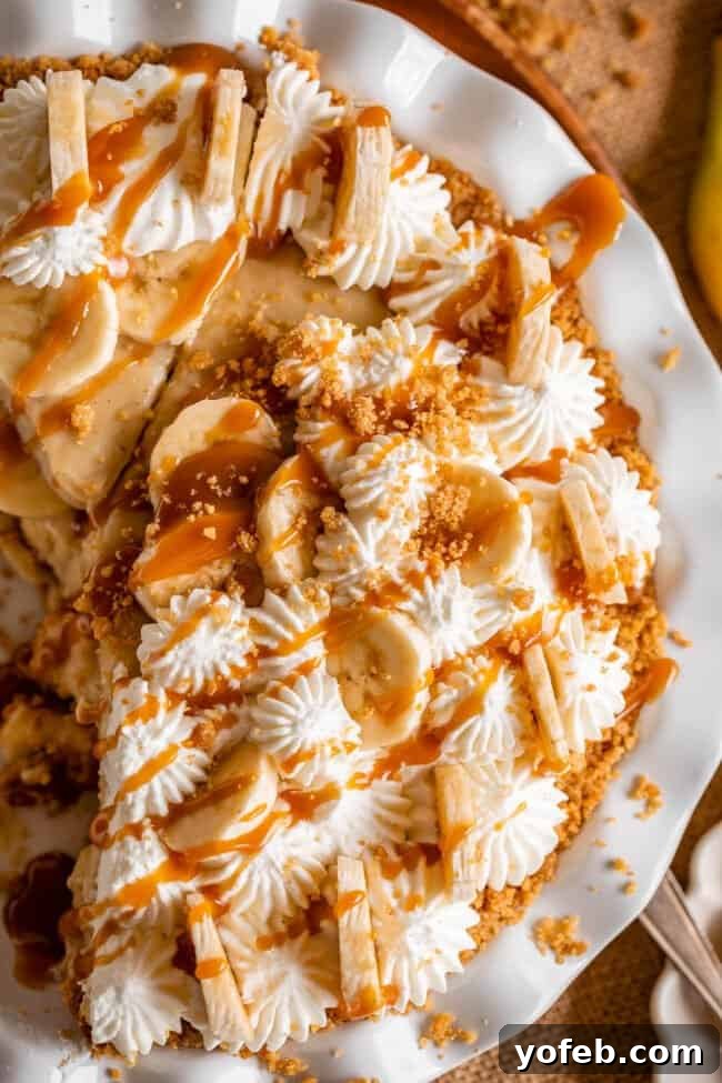 Luscious Banana Cream Pie Recipe 19 A whole banana cream pie in a white pie plate, beautifully drizzled with rich caramel sauce and sprinkled with a coarse graham cracker crumble.