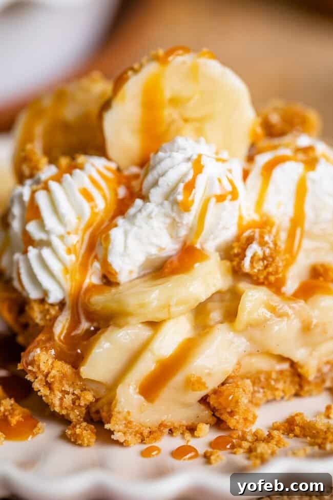 Luscious Banana Cream Pie Recipe 8 A close-up of a slice of banana cream pie on a plate, lavishly drizzled with caramel sauce and sprinkled with graham cracker crumbs.