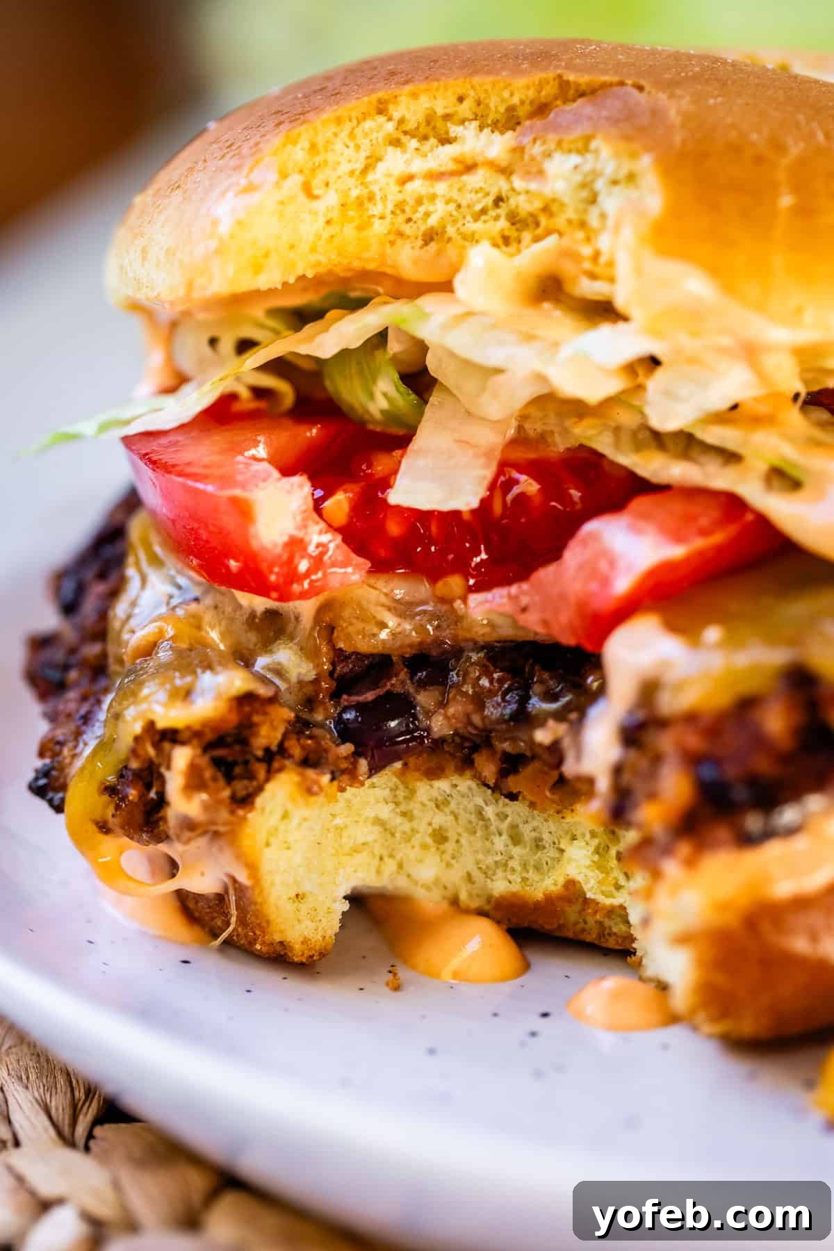 Savory Black Bean Burgers with Fiery Sriracha Aioli 12 A close-up of a black bean burger with a bite taken out, showing its texture and fresh ingredients.