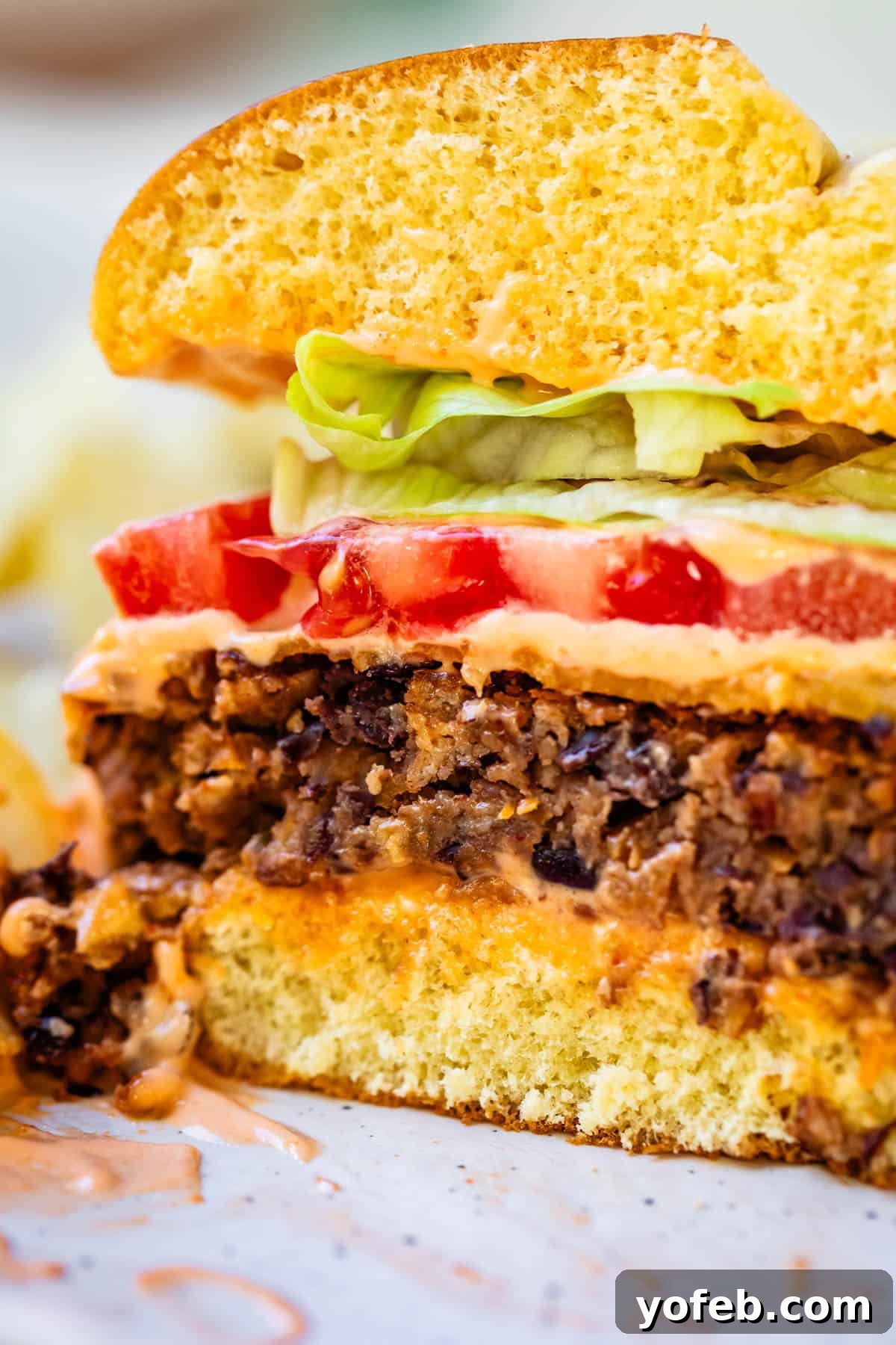 Savory Black Bean Burgers with Fiery Sriracha Aioli 3 A vibrant black bean burger patty, perfectly sliced in half to show its rich, textured interior of beans and vegetables.