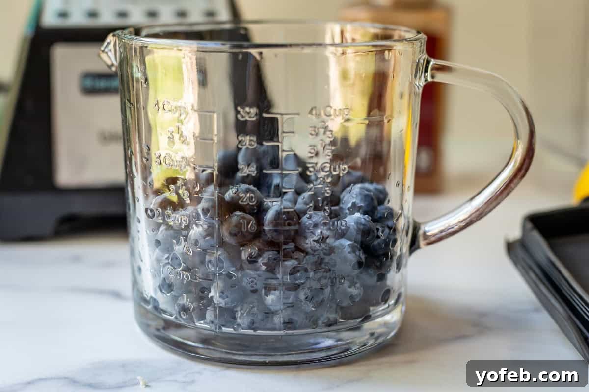 Grandma's Classic Blueberry Pie 13 A glass measuring cup filled with approximately 2 cups of fresh, ripe blueberries, ready for preparation.