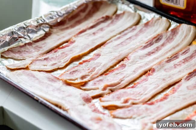 Zesty Lemon Bacon Pea Pasta 6 Raw bacon strips neatly arranged on a foil-lined baking sheet, prepared for oven baking.