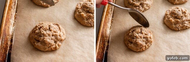 The Ultimate Peanut Butter Butterfinger Cookie 18 A golden-brown Butterfinger cookie fresh from the oven, being gently pushed in on itself with a spoon on a sheet pan. This technique helps create a thicker, chewier center.