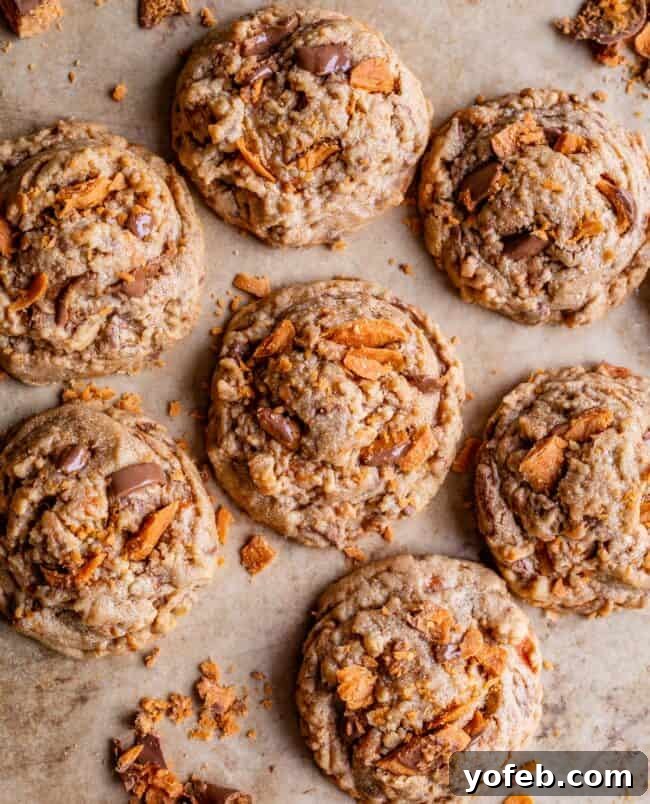 The Ultimate Peanut Butter Butterfinger Cookie 10 An inviting overhead view of freshly baked Peanut Butter Butterfinger Cookies cooling on a parchment-lined baking sheet, showcasing their perfectly rounded shape and delicious golden-brown crust.