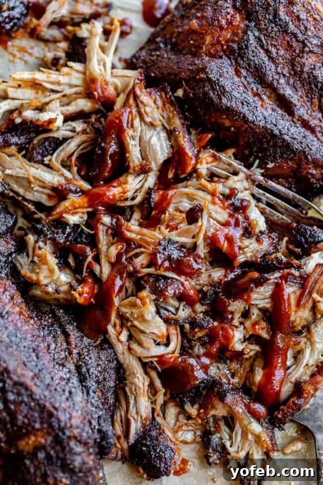 Melt In Your Mouth Pulled Pork Slow Cooker Or Oven 19 pulled pork made in the oven shredded on parchment paper with bbq sauce.