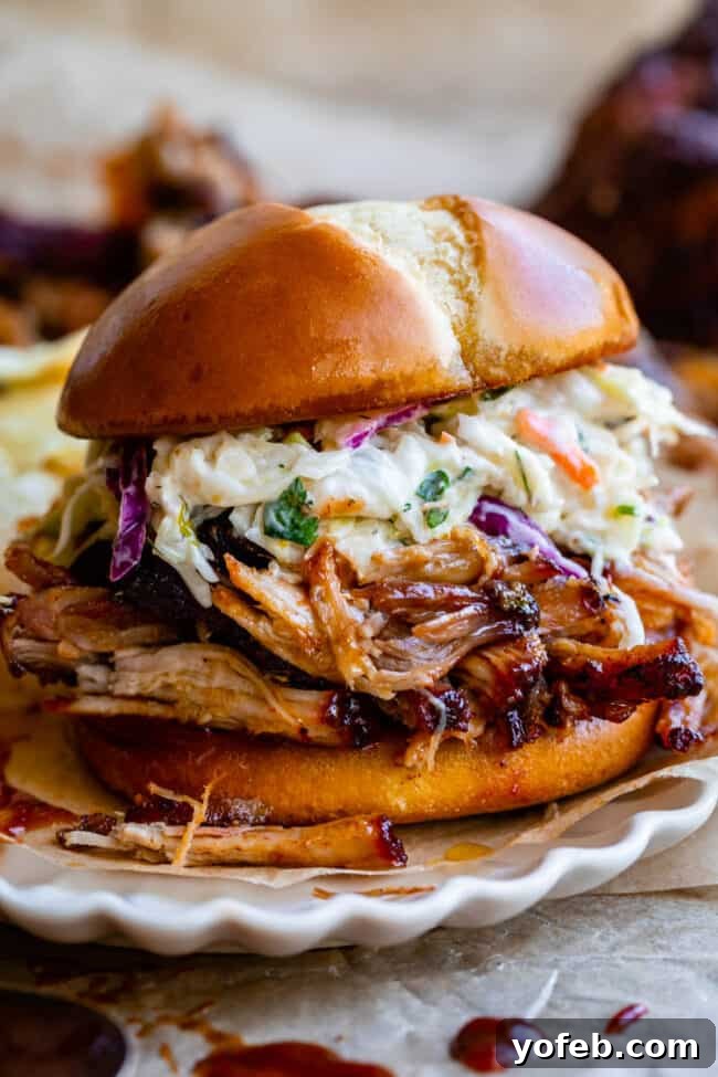 Melt In Your Mouth Pulled Pork Slow Cooker Or Oven 22 pulled pork sandwich with coleslaw on a white plate.