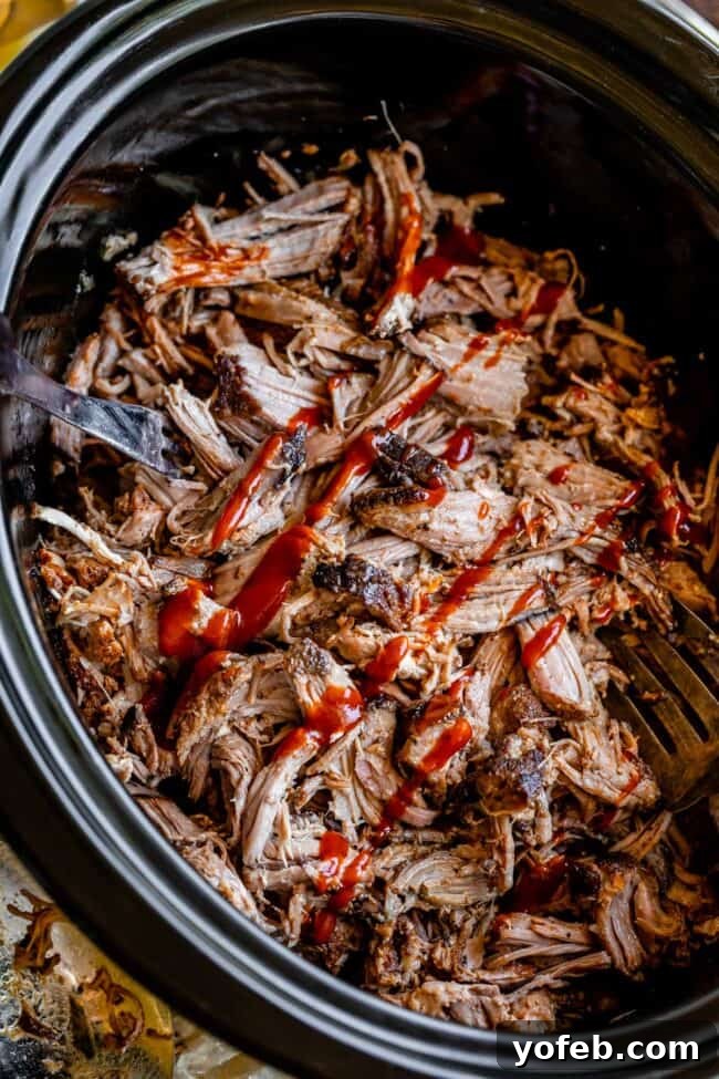 Melt In Your Mouth Pulled Pork Slow Cooker Or Oven 6 crock pot pulled pork shredded in a black crock pot.